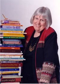 Margaret Read MacDonald stands next to her collection of books she has authered. 